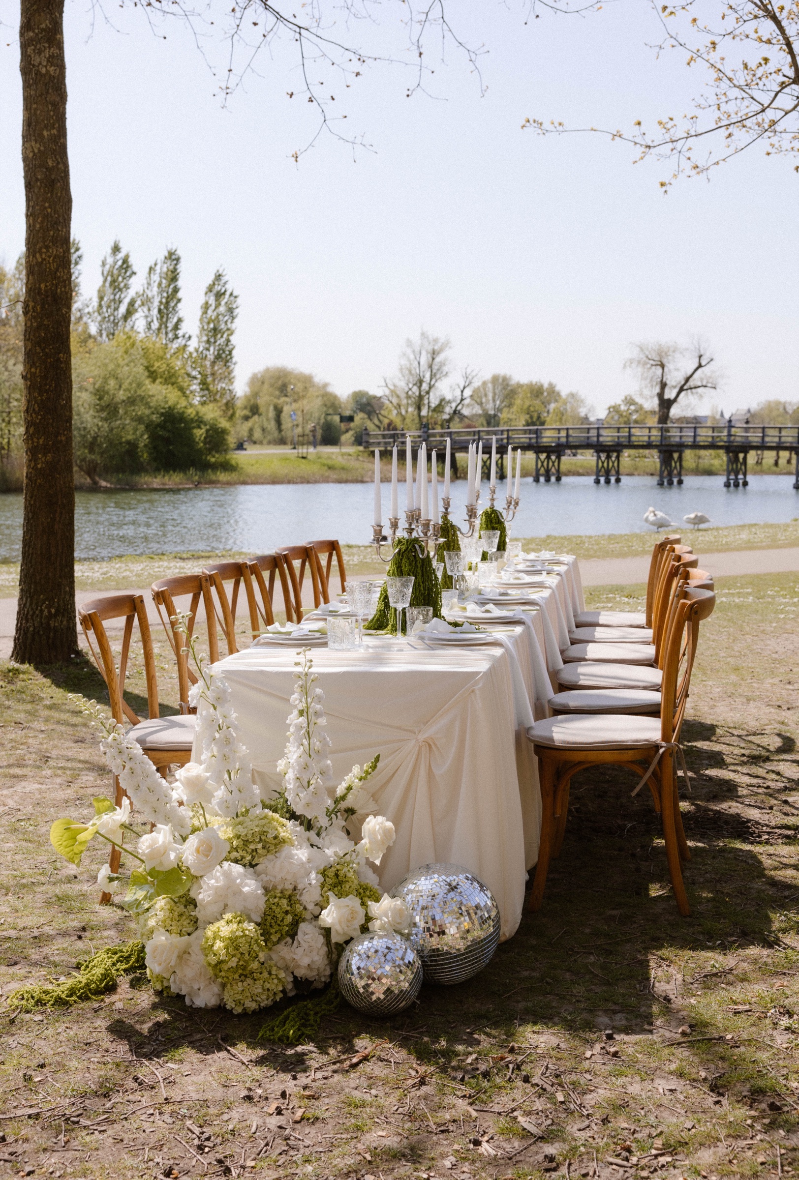 Bruiloft diner aan het water met discoballen en bloemen