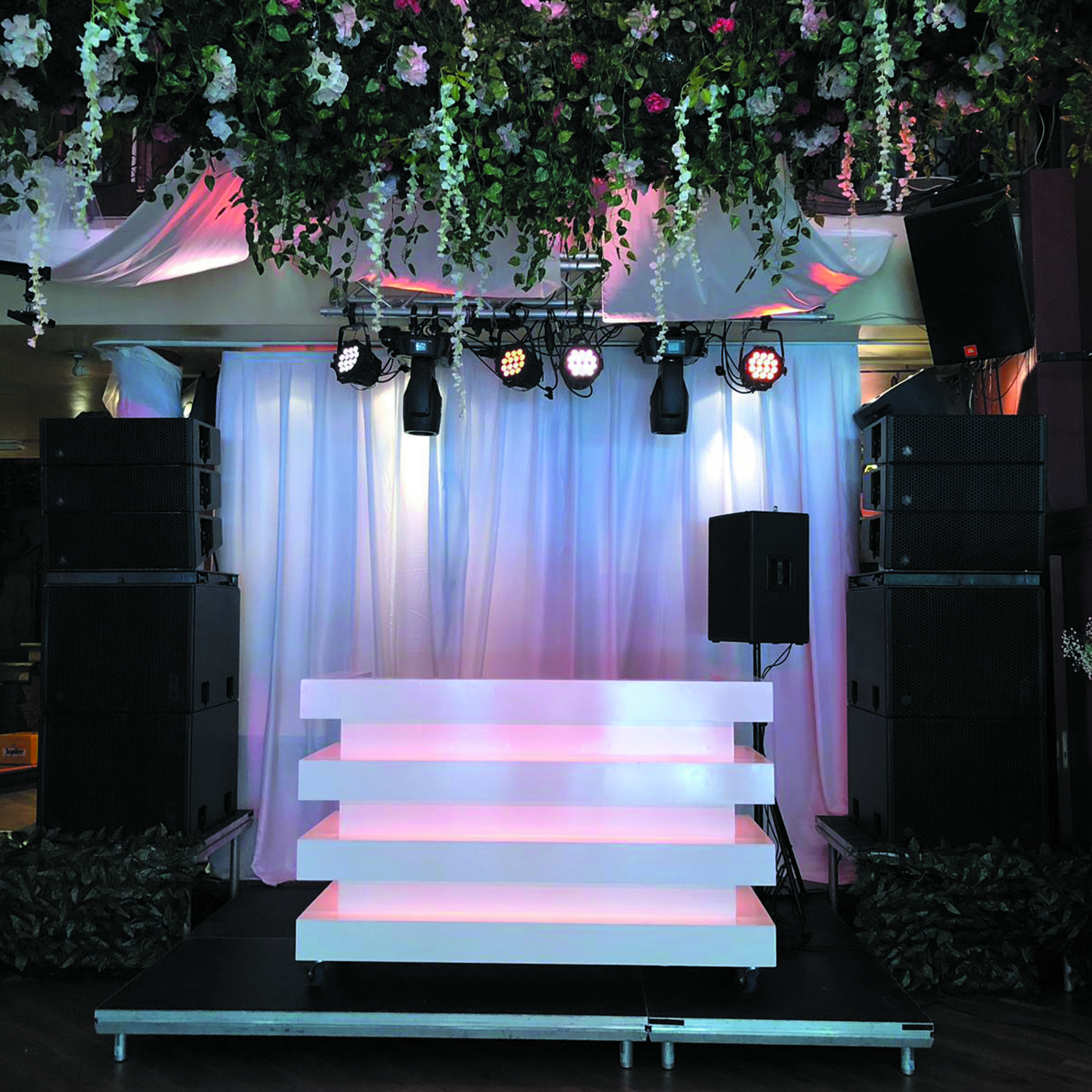 DJ podium met bloemeninstallatie, stage lighting en speakers - festival sfeer